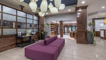 A lobby with a reception desk, a seating area, and a store.