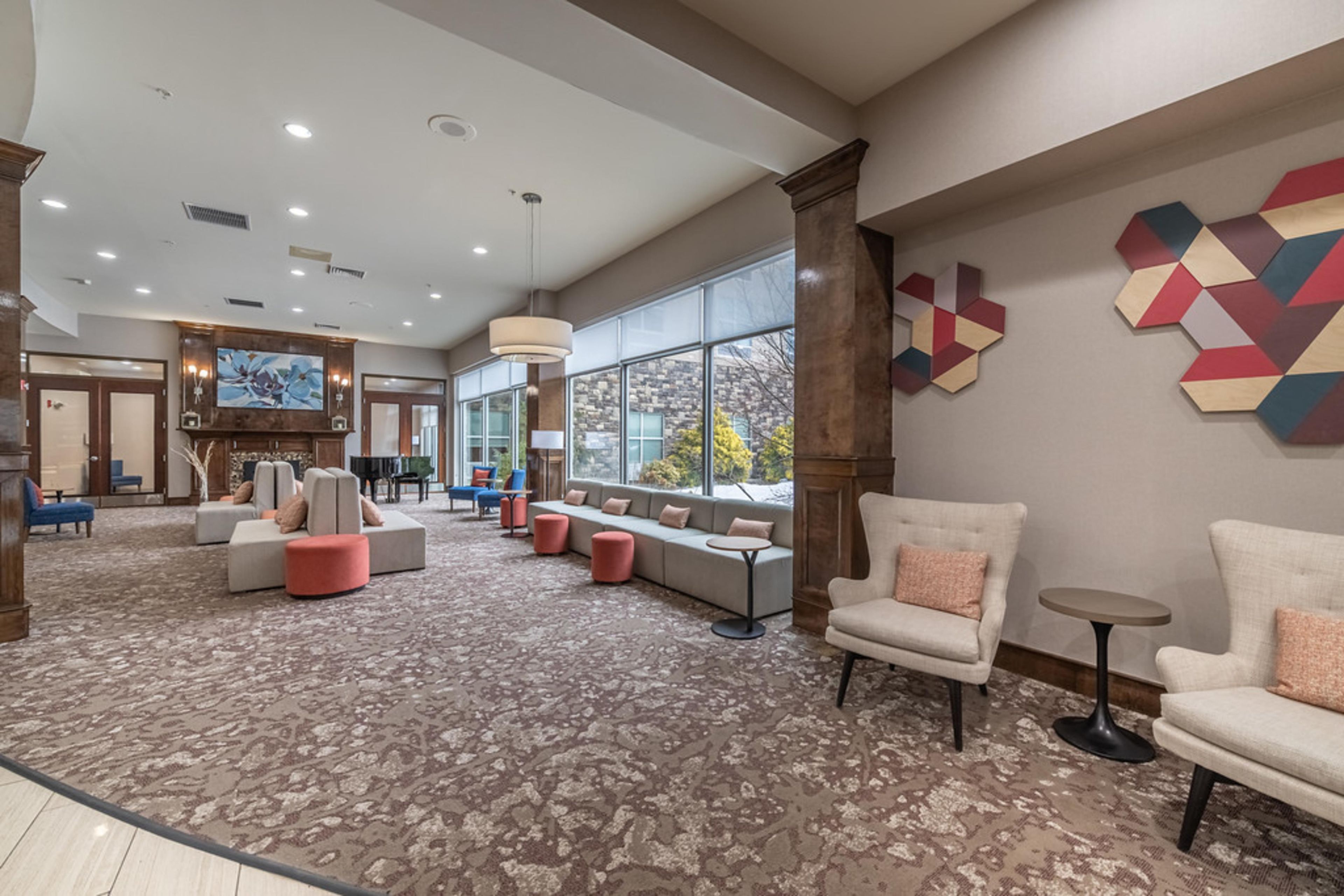 Un hall d’entrée spacieux, doté d’un tapis à motifs, de coins salon et de grandes fenêtres.