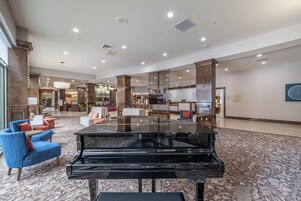 A spacious lobby with a grand piano, comfortable seating, and a modern interior design.