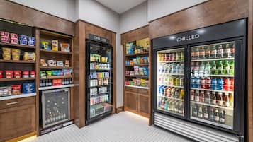 A refrigerated beverage display with a 'CHILLED' sign, surrounded by shelves stocked with snacks and beverages.