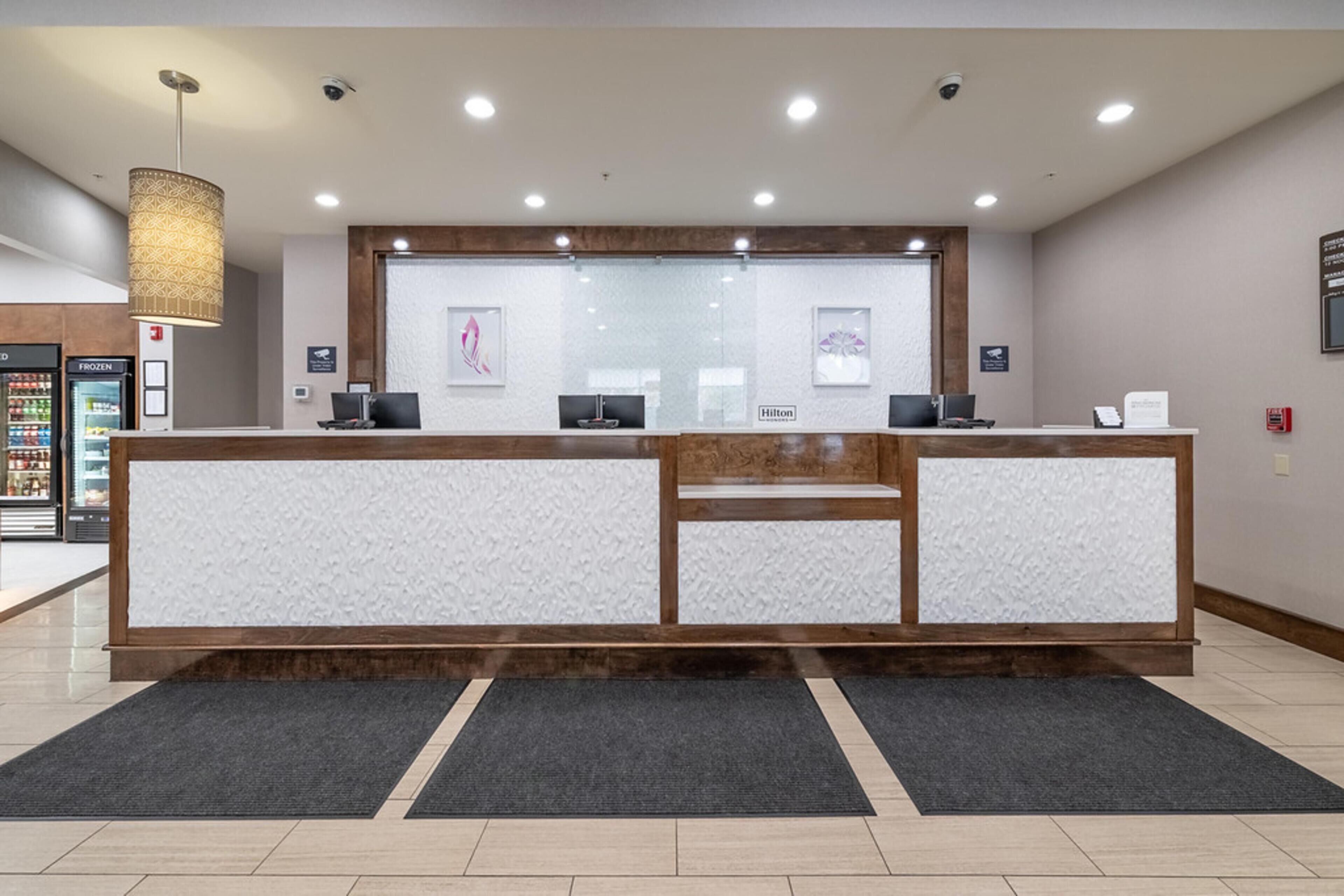 A reception desk with a white and wooden design, two computers, a fire extinguisher, and a 'Hilton' sign.