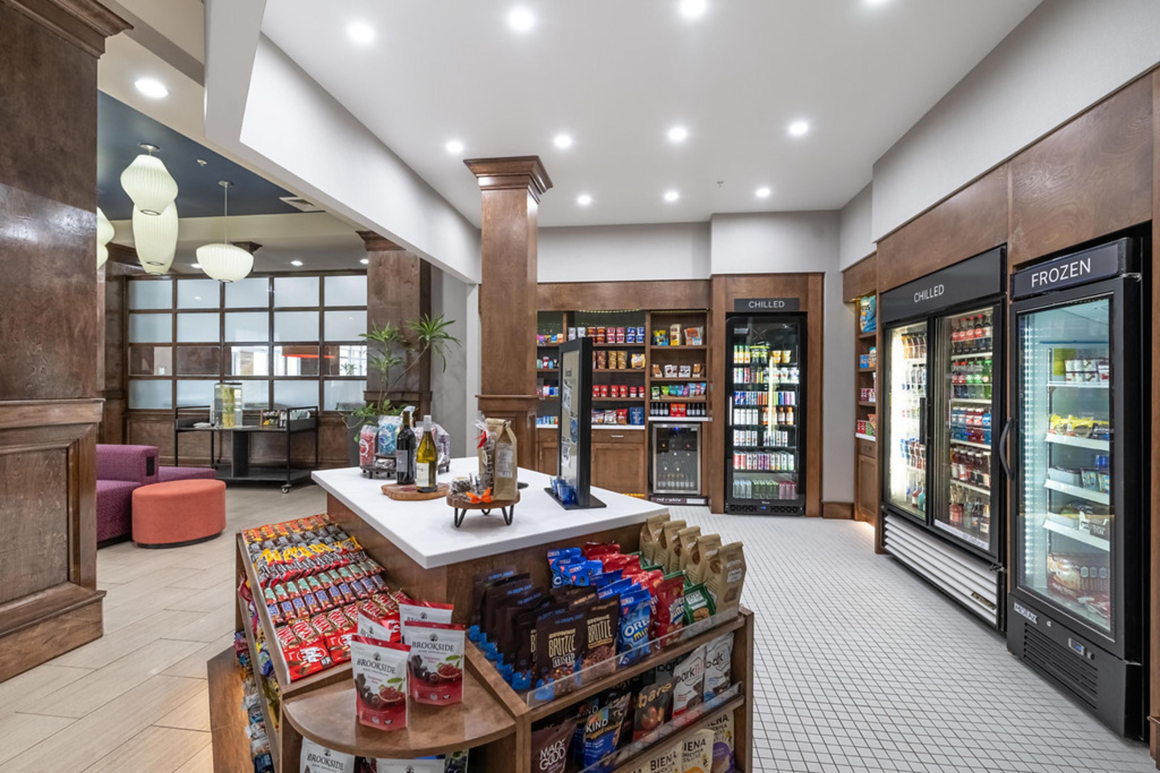 A spacious lobby with a central island display, refrigerated beverage cases, and a seating area.
