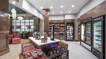 A spacious lobby with a central island display, refrigerated beverage cases, and a seating area.