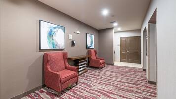 A hallway with two red armchairs, a wooden bench, and two abstract paintings on the wall.