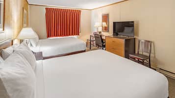 A hotel room with two beds, a desk, a chair, a television, and a lamp.