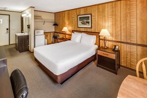A hotel room with a bed, bedside tables, a desk, a chair, and a wooden wall panel. - Denali Park Hotel (Healy)