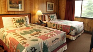 Quarto com duas camas, paredes de madeira, quadros enquadrados, janela com vista e mesa de cabeceira com abajur.