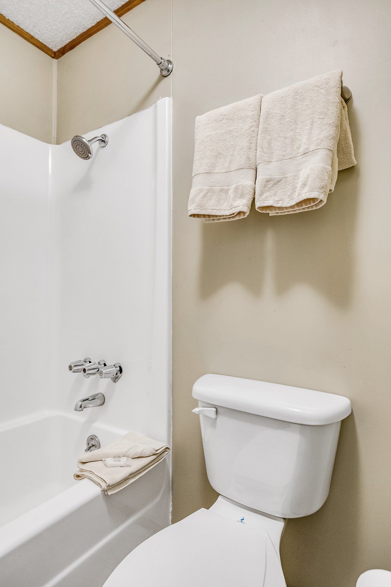 A bathroom with a bathtub, toilet, and a towel rack with two towels.