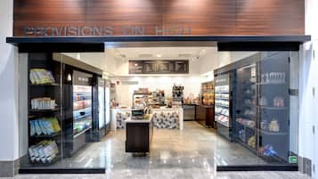 A store named "Provisions on High" with a modern interior, featuring a central counter and glass display cases filled with snacks and beverages.