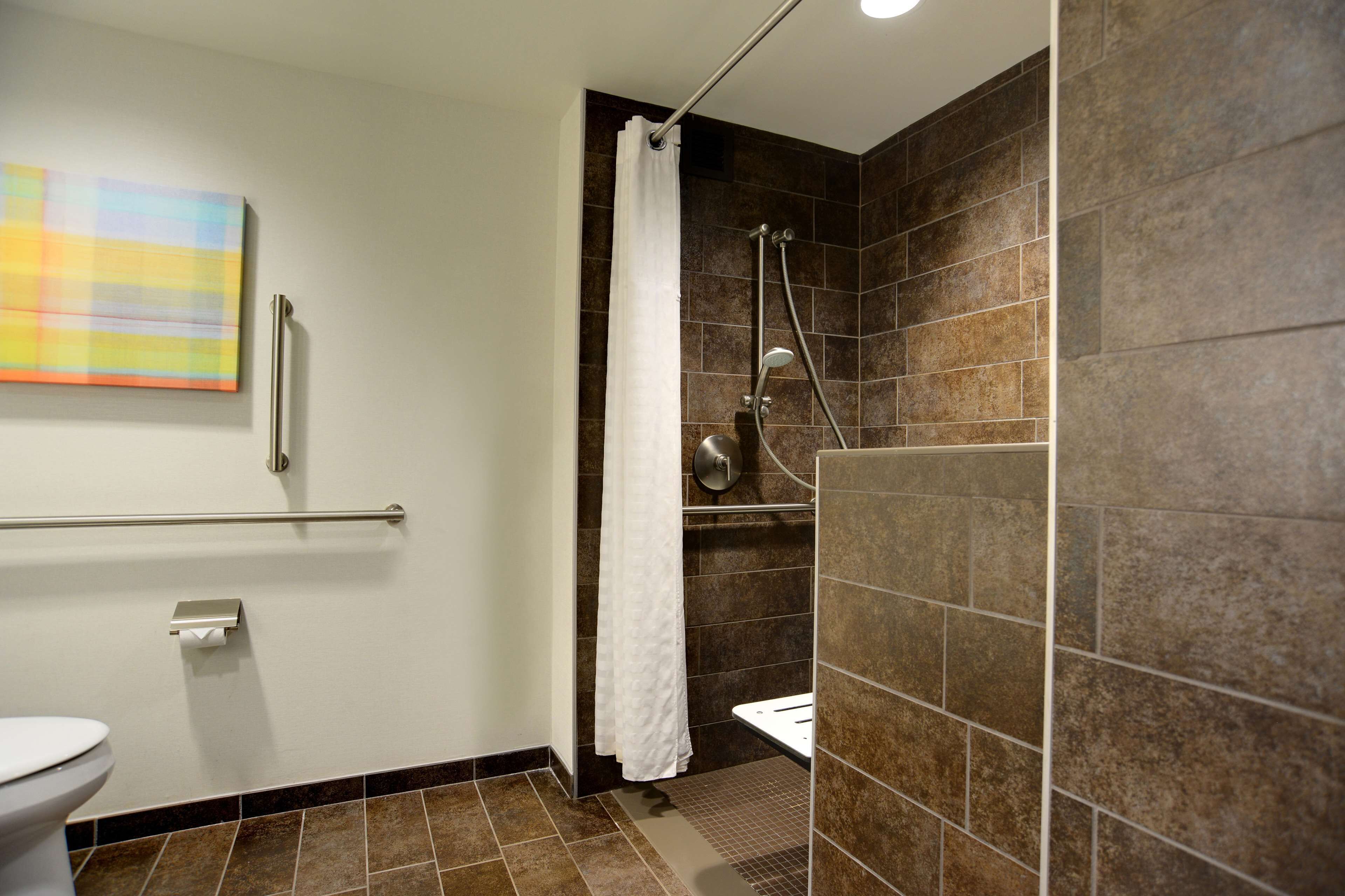 A modern bathroom with a shower, toilet, and a towel rack.