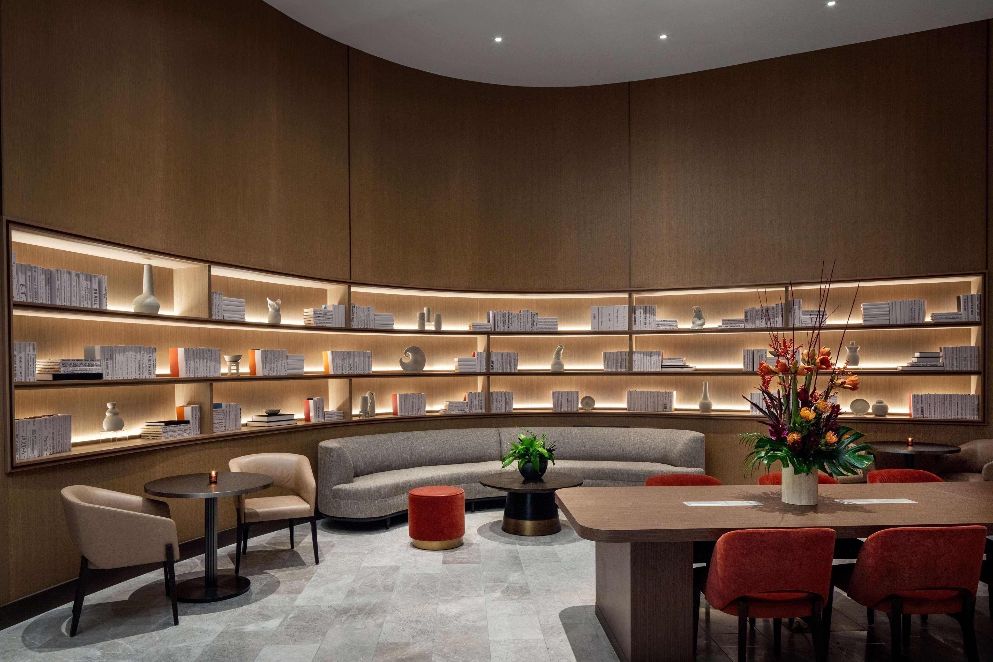 A modern library with bookshelves, a sofa, and a dining area.