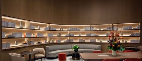 A modern library with bookshelves, a sofa, and a dining area.