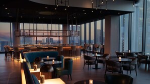 A modern bar area with seating, large windows, and a city view. - Hilton Columbus Downtown (Columbus)