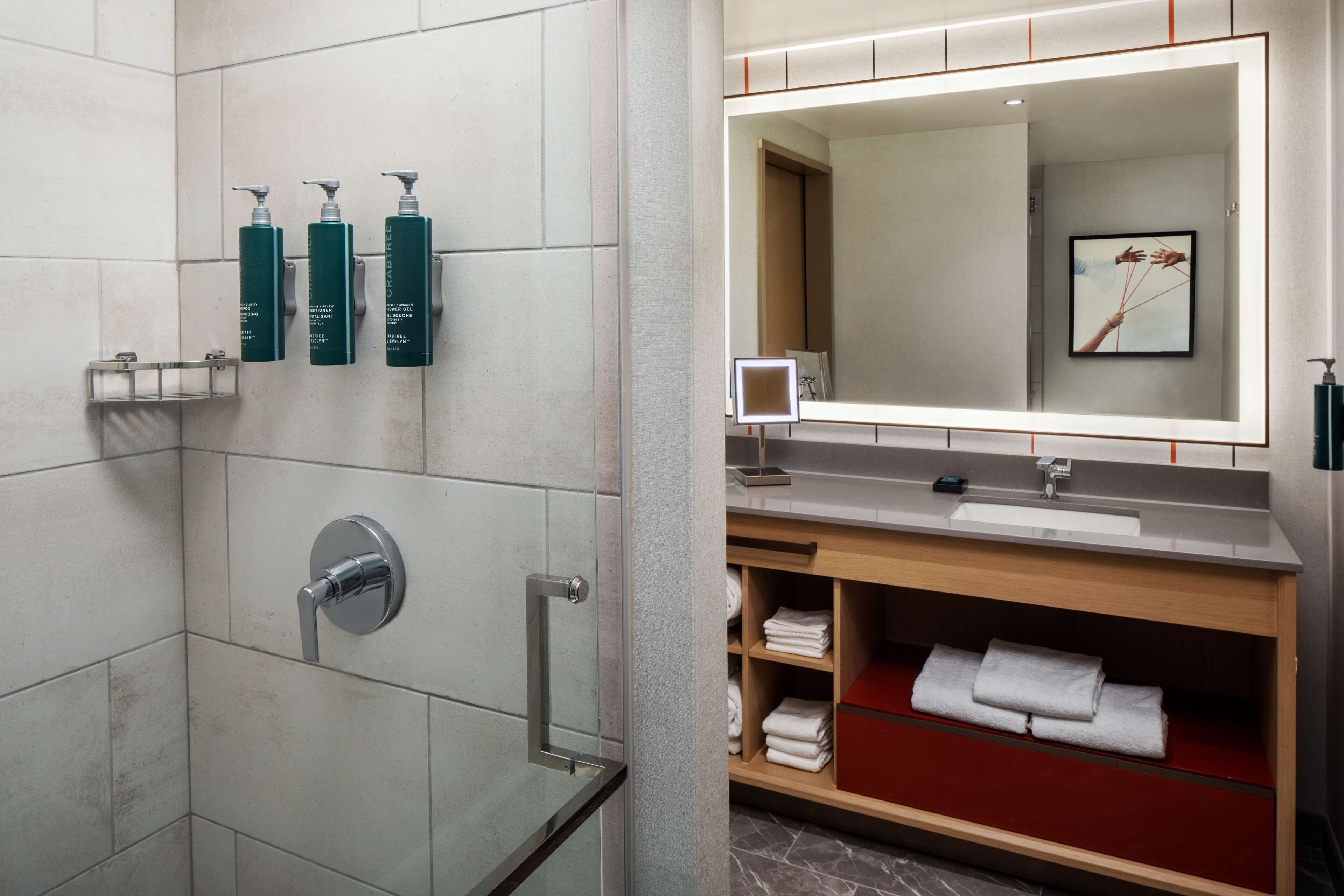 Une salle de bain moderne avec une douche à parois de verre, un meuble-lavabo avec un miroir et des serviettes soigneusement pliées.