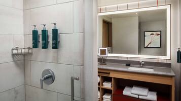 Une salle de bain moderne avec une douche à parois de verre, un meuble-lavabo avec un miroir et des serviettes soigneusement pliées.