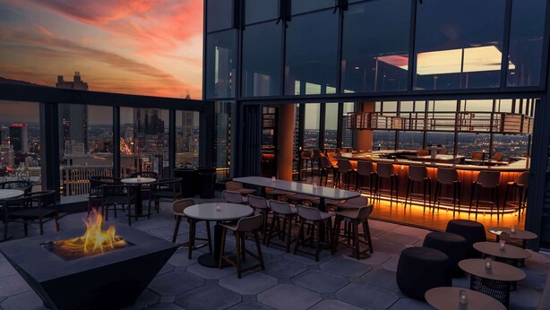 A rooftop bar with a fire feature, tables, and chairs, offering a city view. - Hilton Columbus Downtown (Columbus)