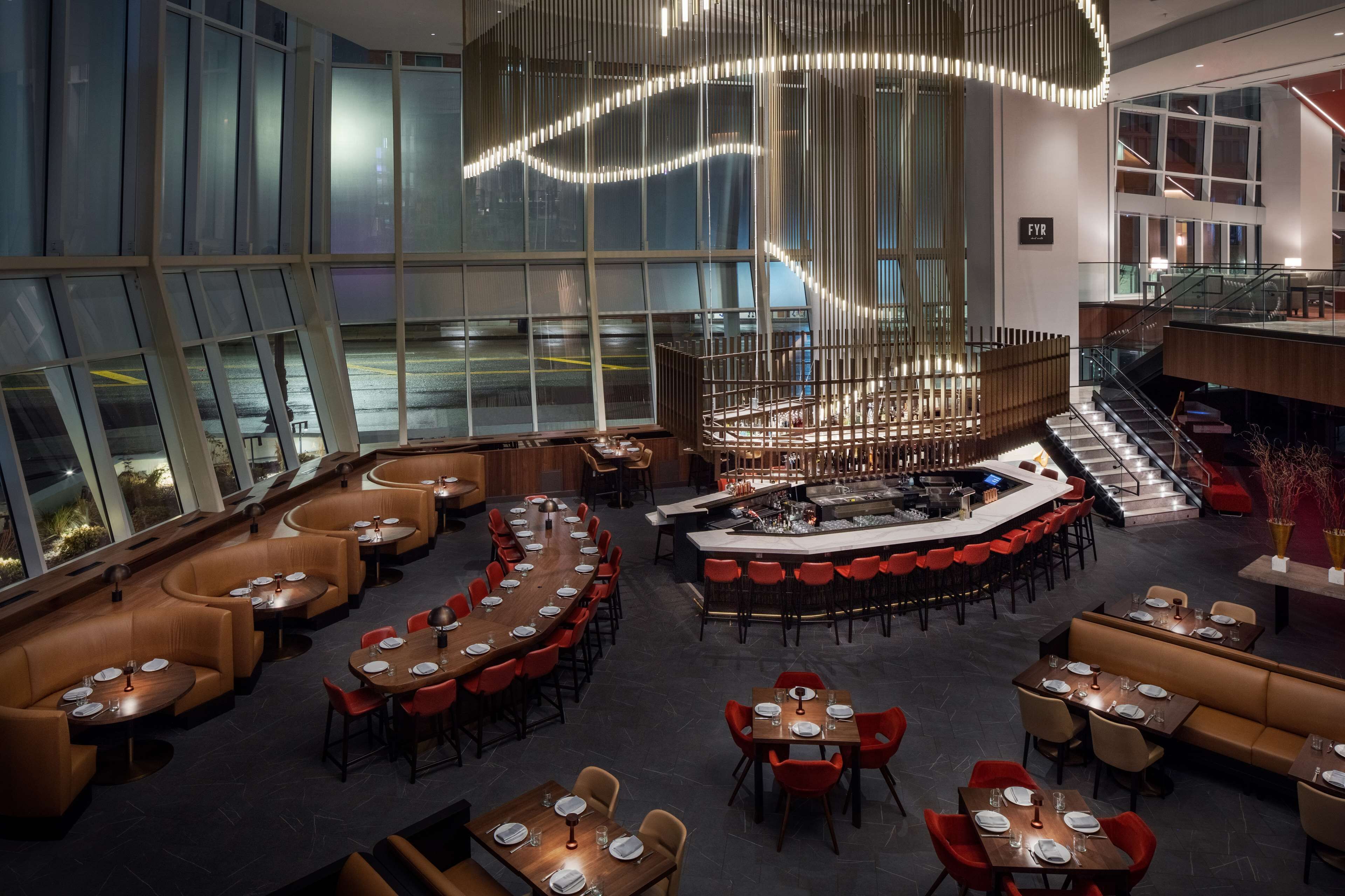Un espacio interior amplio con diversas opciones de asientos, incluyendo mesas redondas y cabinas, y una zona de bar central.
