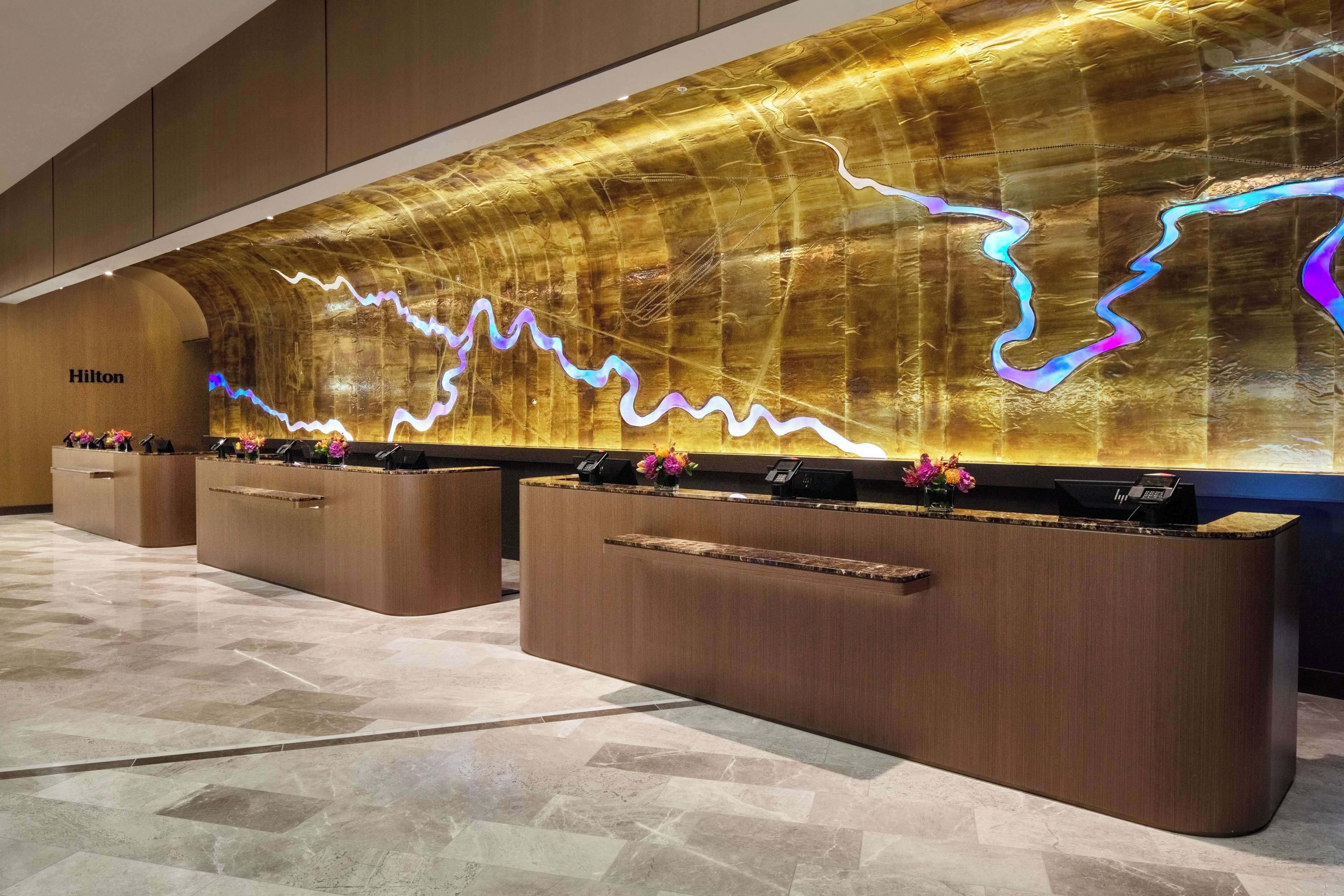 A reception area with a modern design, featuring a large, illuminated wall display and a wooden reception desk.