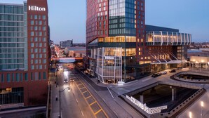 A Hilton hotel with a modern glass facade, a convention center, and a well-lit urban street. - Hilton Columbus Downtown (Columbus)