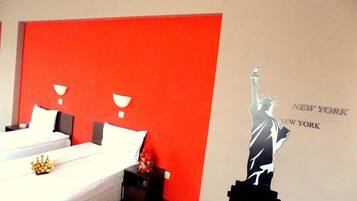 A hotel room with a large bed, a nightstand, and a wall with a New York City skyline mural.