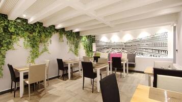 A modern dining area with tables and chairs, a ceiling with a unique pattern, and a wall with a large black and white mural.