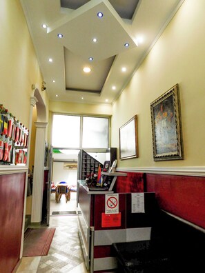 Un hall d’hôtel avec un comptoir d’accueil, une œuvre d’art encadrée au mur et un escalier menant à un autre étage.