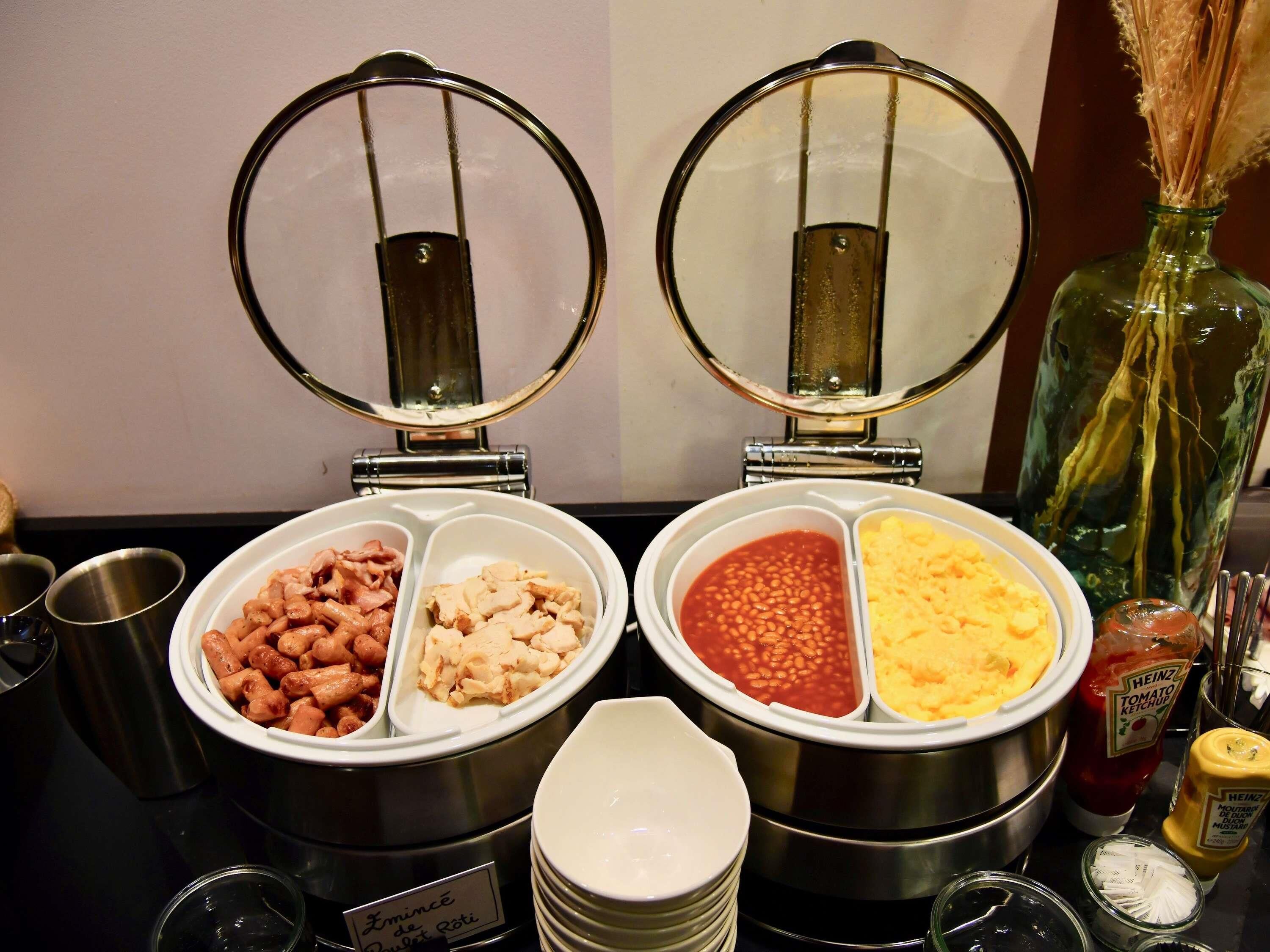 Un buffet proposant un large choix de plats, notamment des haricots, des macaronis et diverses sauces.