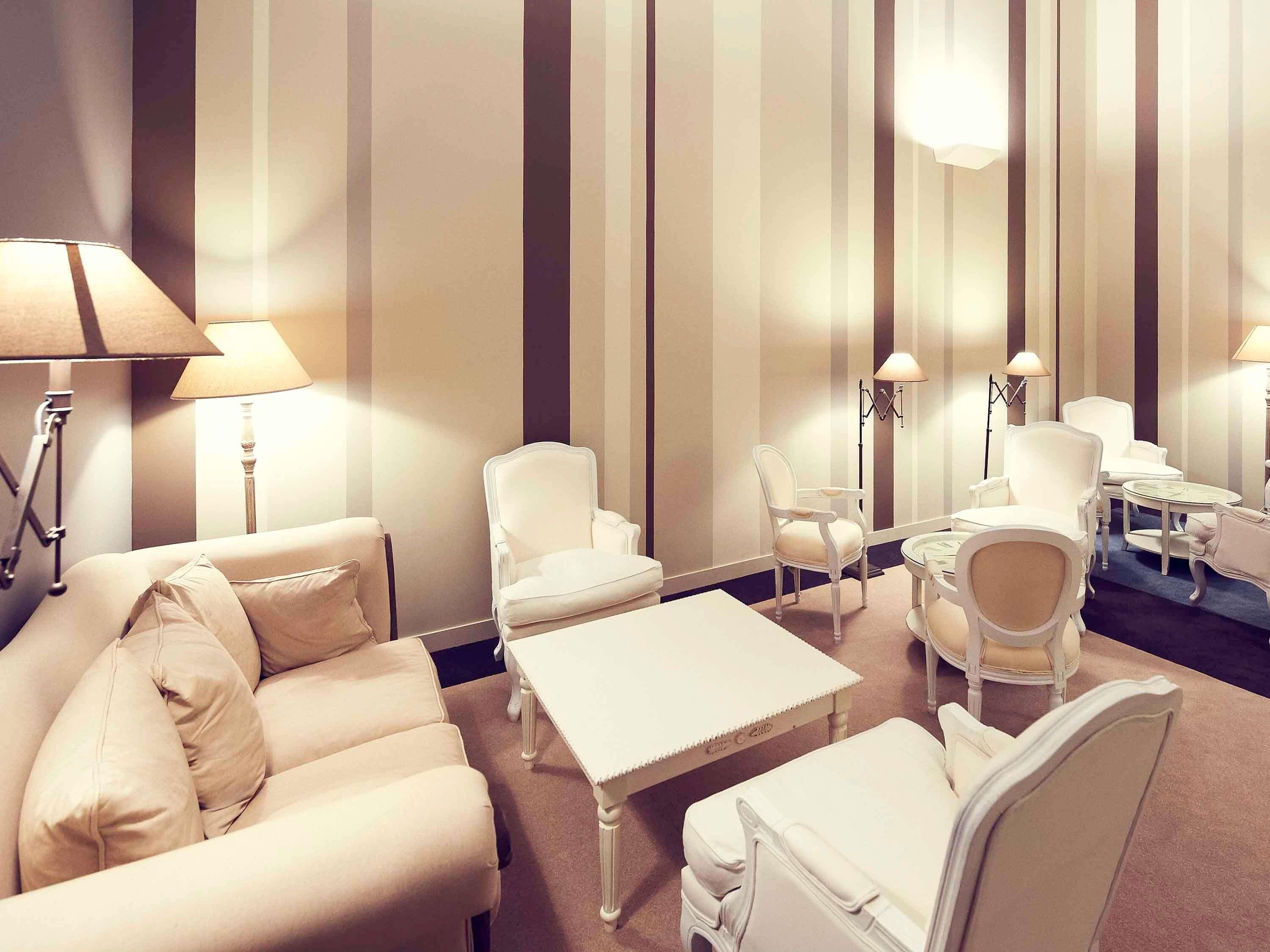 A hotel room with a striped wall, a sofa, a coffee table, and two armchairs.