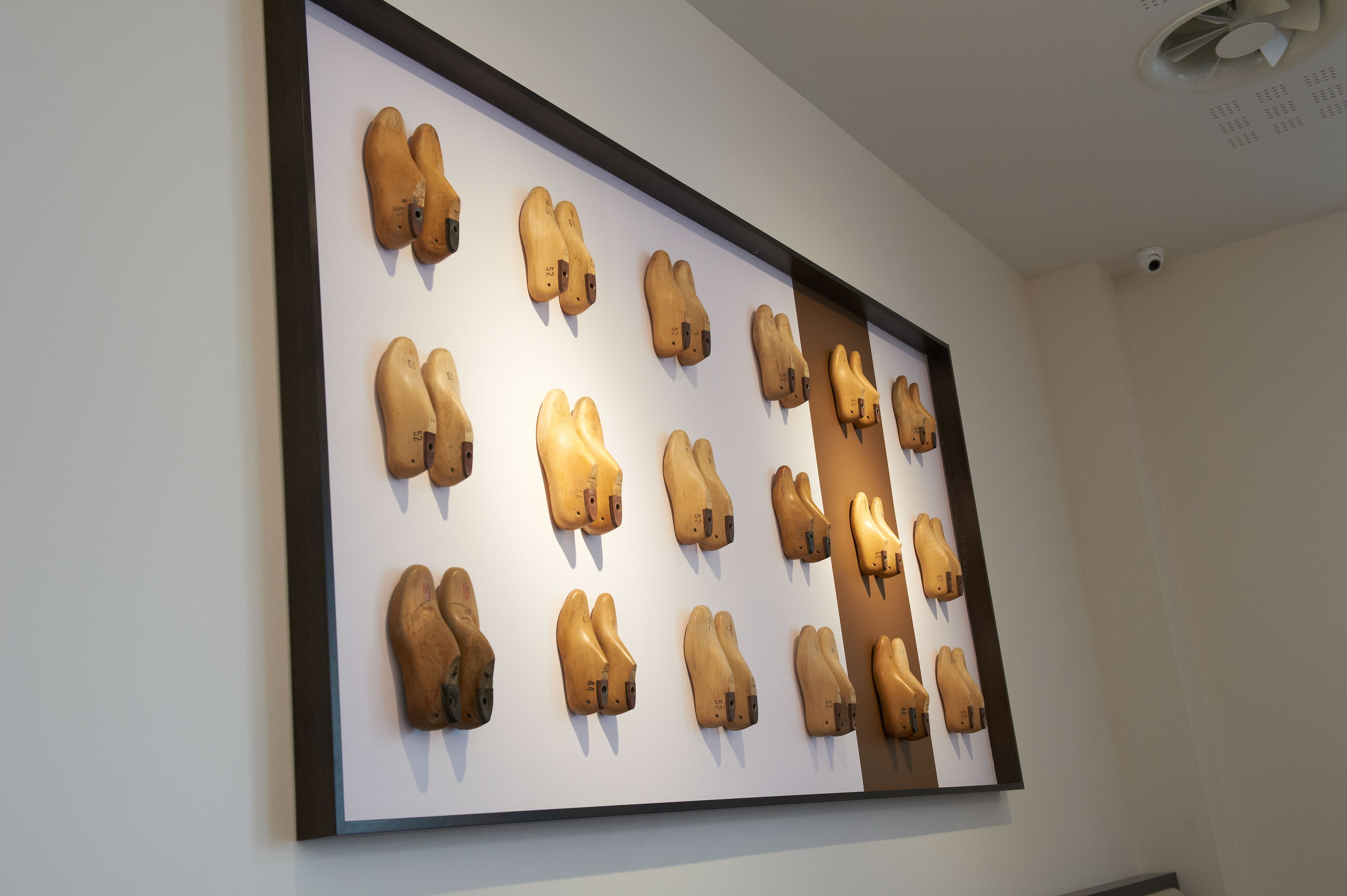A framed collection of wooden shoe heads on a wall.