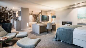 Quarto de hotel moderno com cama, escrivaninha, cadeira, sofá e uma grande planta em vaso.