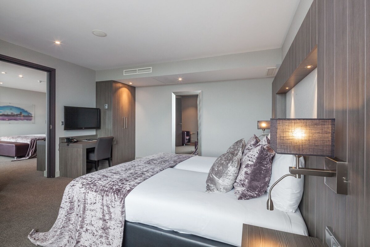Een moderne hotelkamer met een bed, bedlampje en een televisie.