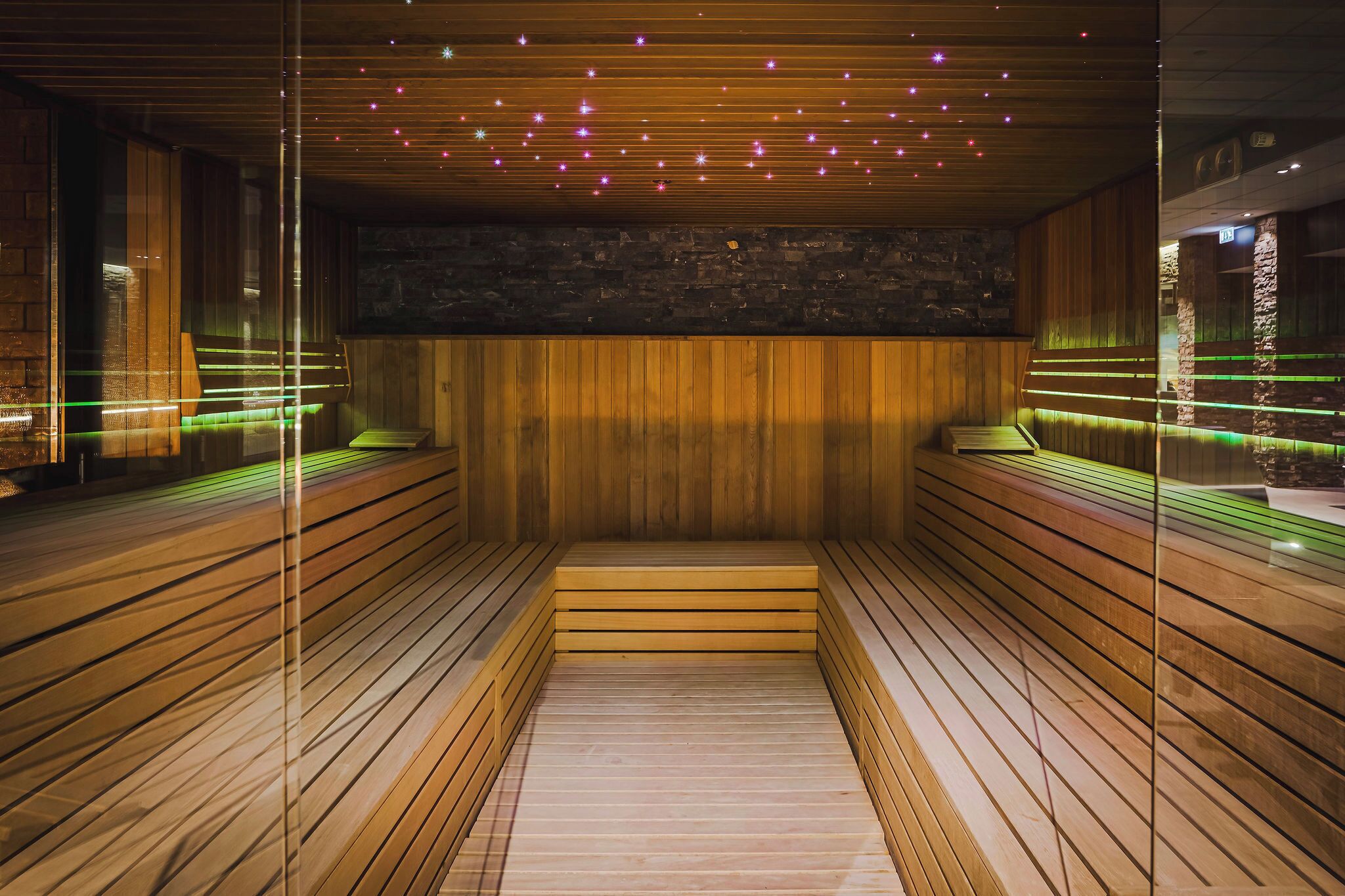 A sauna with wooden benches and a stone wall.