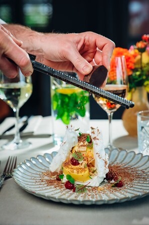 A person using a grater to prepare a dessert on a plate.