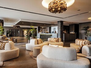 A modern lobby with round seating, a reception desk, and decorative plants.