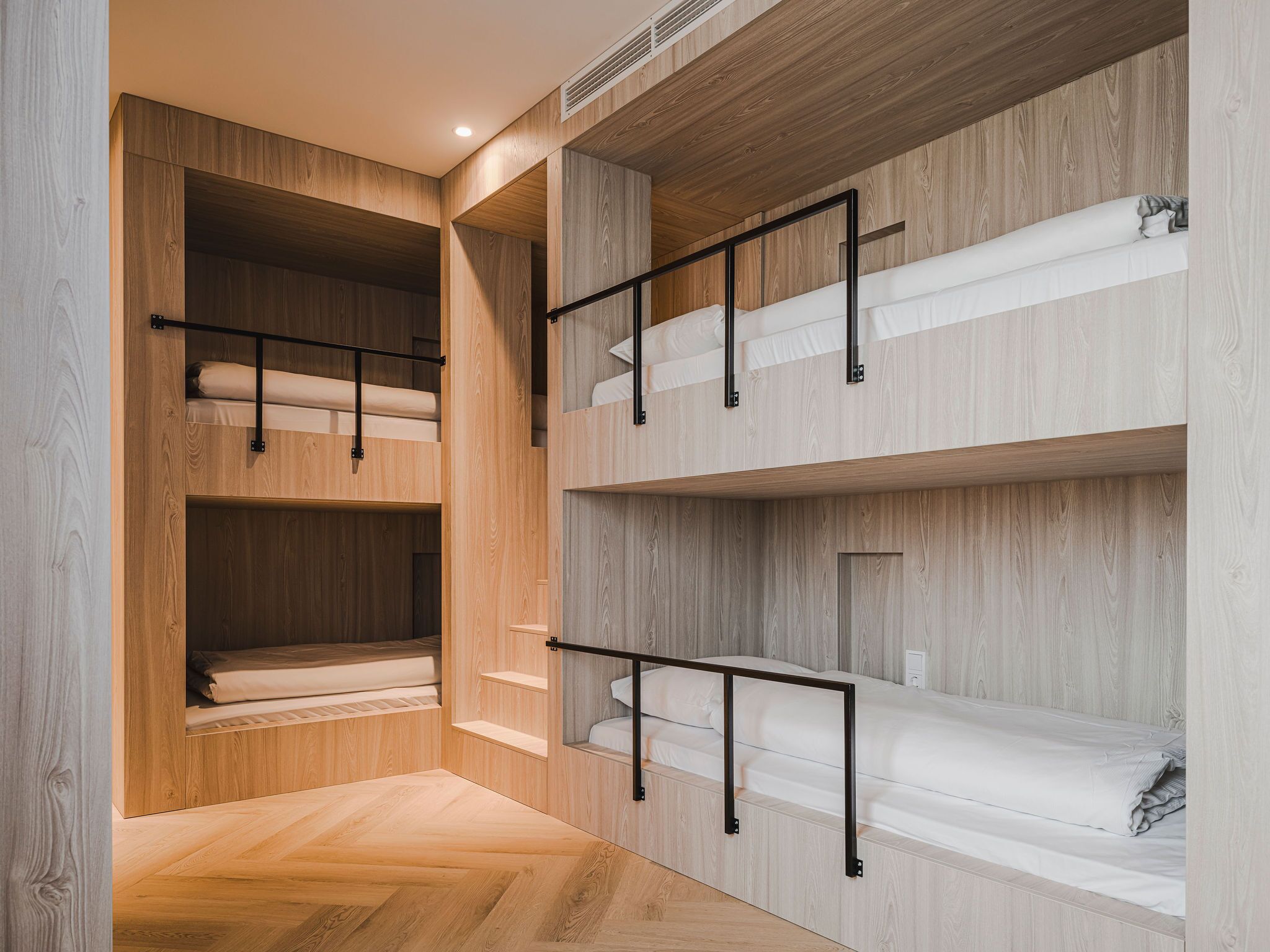 A multi-level bunk bed room with wooden walls and metal railings.
