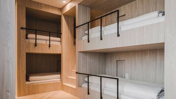 A multi-level bunk bed room with wooden walls and metal railings.