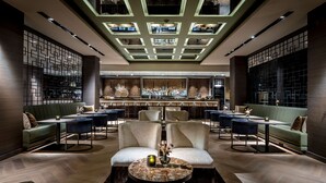 Een moderne barruimte met een centrale zithoek, een bar en een decoratief plafond.