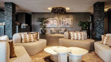 A modern lounge area with plush sofas, a central coffee table, and a large plant.