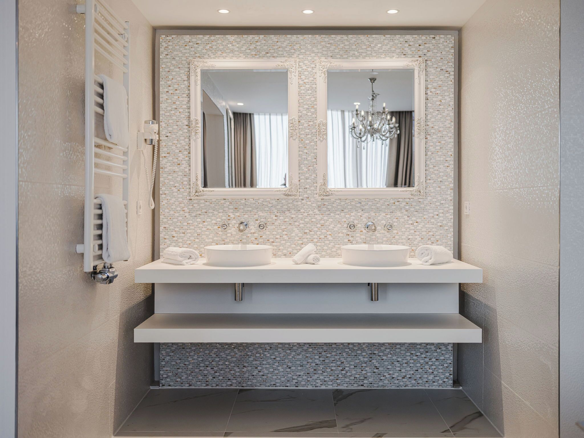Un baño moderno con dos lavamanos, un espejo grande y un perchero para toallas.