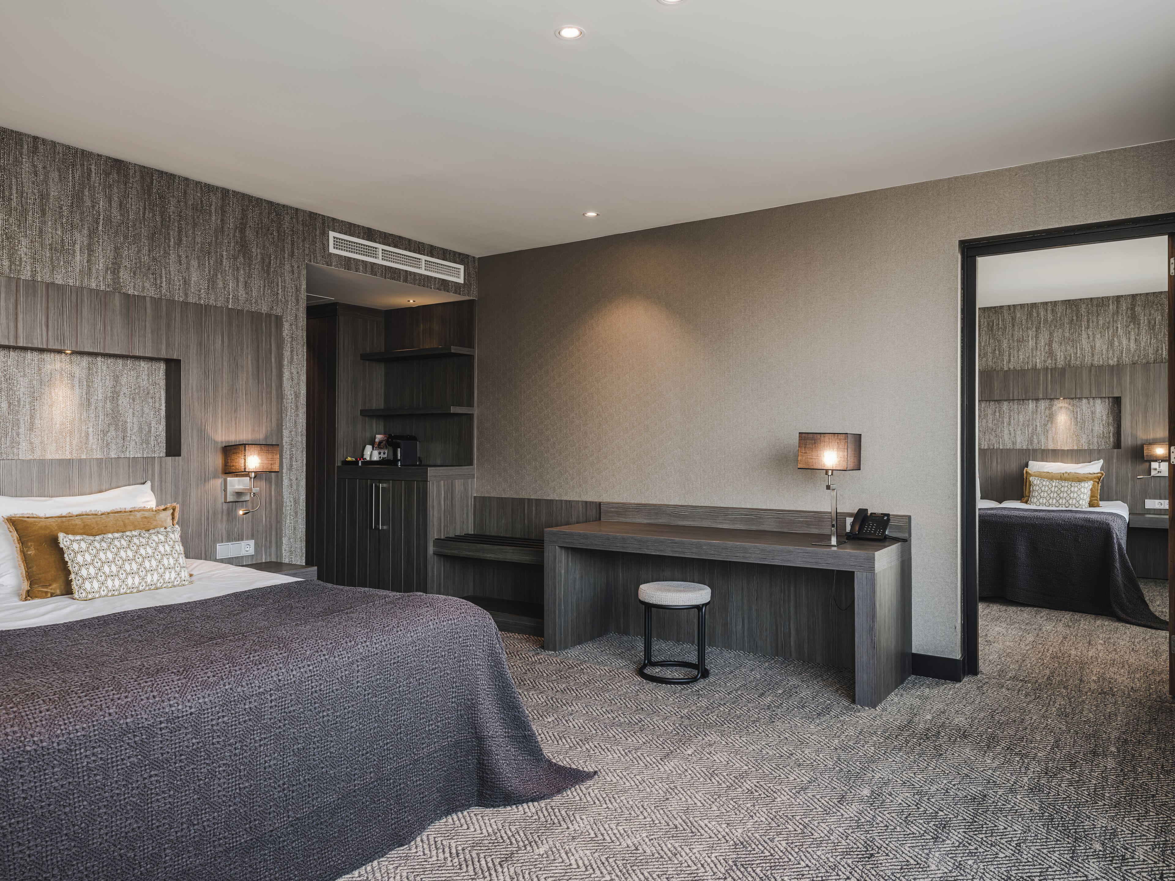 A modern hotel room with a large bed, a desk, and a mirror.