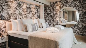 Quarto moderno com cama grande, telefone de cabeceira e espelho.