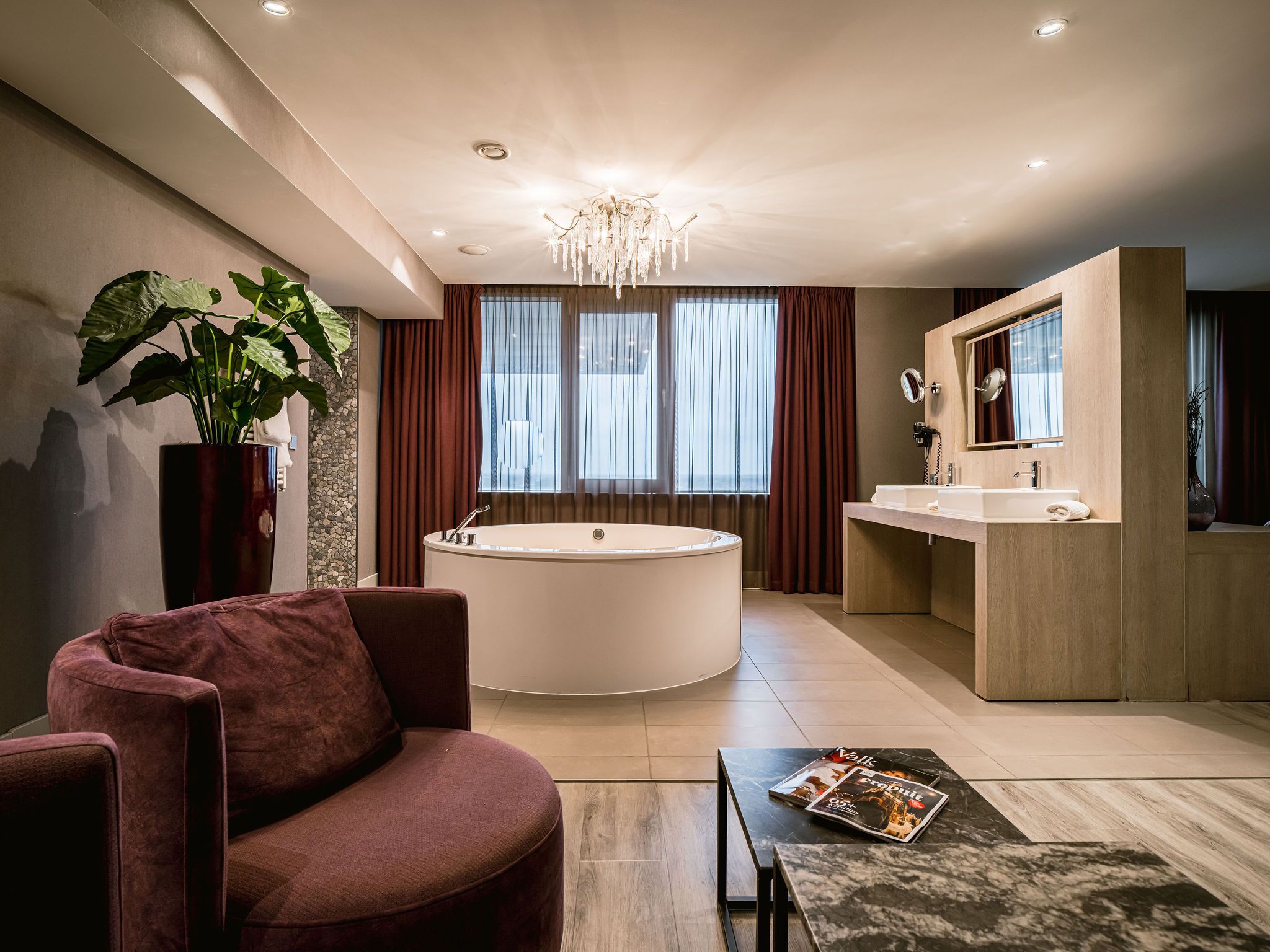 A modern bathroom with a freestanding bathtub, a vanity with a mirror, and a large potted plant.