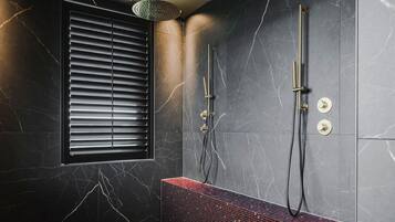 A modern bathroom with a black marble wall, a red mosaic bench, and a window with blinds.