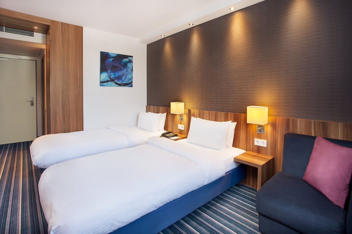 A hotel room with a large bed, two bedside tables, a desk, and a chair.
