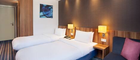 A hotel room with a large bed, two bedside tables, a desk, and a chair.