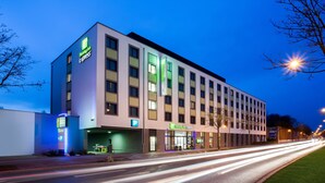 A modern Holiday Inn Express building with a flat facade, multiple windows, and a visible parking sign.