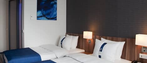 Habitación de hotel con dos camas, una pared oscura con textura, un cuadro y un teléfono en la mesita de noche.