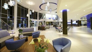 Een ruime lobby met moderne zitplaatsen, een centrale salontafel en decoratieve hanglampen.