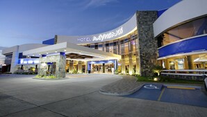Een modern hotel met een opvallende ingang, een terras en een parkeerplaats voor mindervaliden.