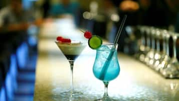 Dos cócteles sobre una barra, con un fondo desenfocado de gente.